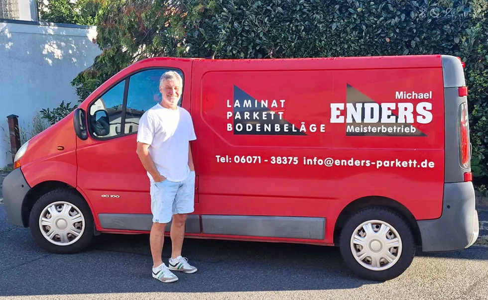 Geschäftsführer Michael Enders vor dem roten Firmenwagen